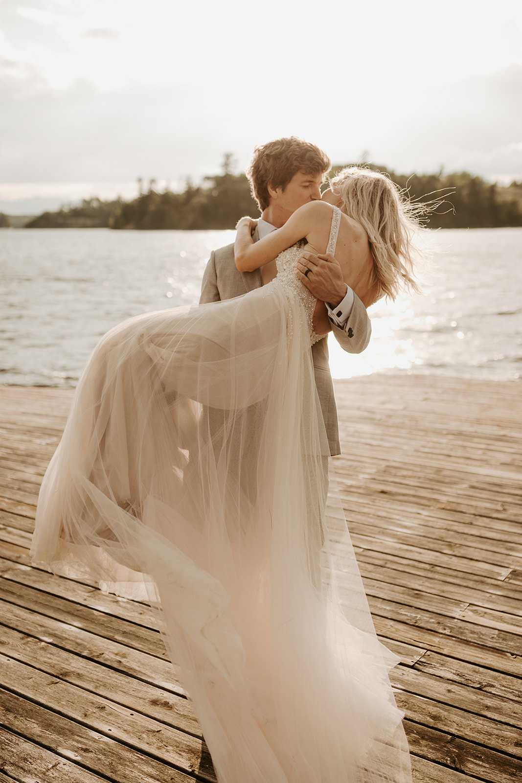 Bride and groom embracing at a dock at sunset during their wedding in Lake of the Woods, Kenora, Ontario,