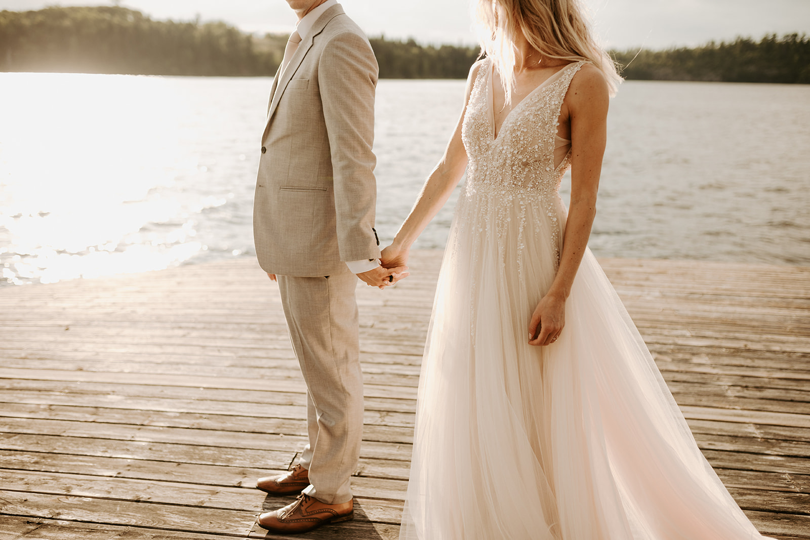 Bride and groom embracing at a dock at sunset during their wedding in Lake of the Woods, Kenora, Ontario,