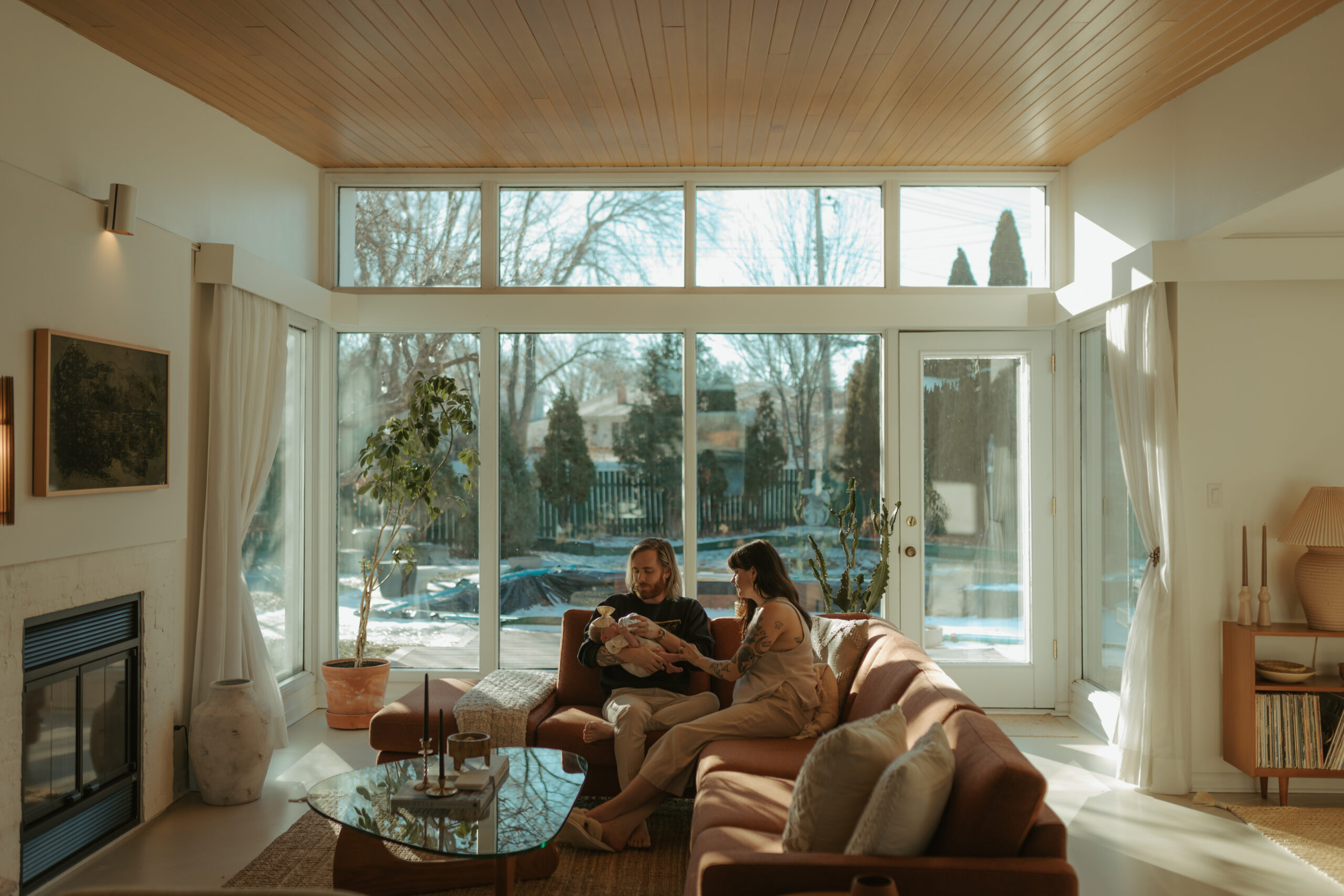 mother and father holding newborn baby in their mid-century modern home in winnipeg, manitoba @thezielkehome